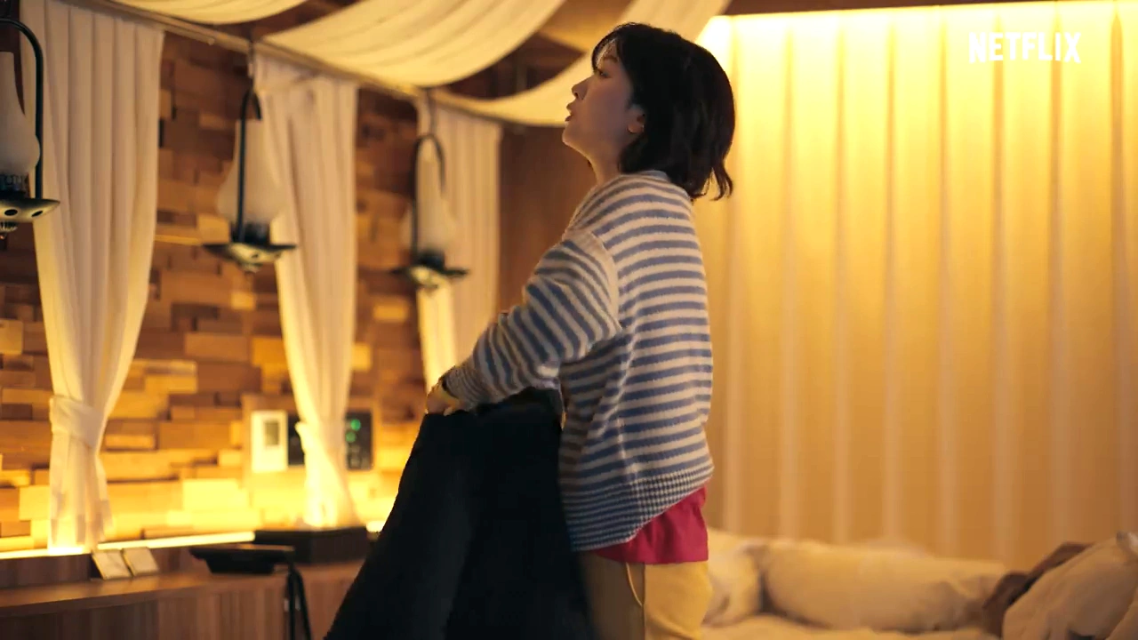 明かりのついた部屋で横を向いて立つ彼女