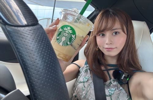 YouTuberあま猫がグリーン系オフショルダートップでスポーツカーの運転席からスターバックスのフラペチーノを手に笑顔のセルフィー。車内Vlogの爽やかな瞬間がSNSで人気の車好きYouTuberの魅力。